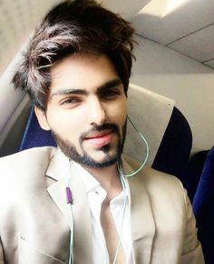 a man in a suit and headphones sitting on an airplane looking at the camera