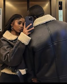 a woman taking a selfie in front of a man wearing a black leather jacket