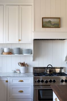 a stove top oven sitting inside of a kitchen next to white cupboards and drawers