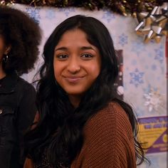 two young women standing next to each other in front of a christmas tree and decorations