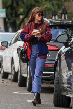 a woman walking down the street while holding a cup