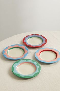 four colorful plates sitting on top of a white table