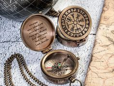 two antique compasss sitting on top of a map next to a pocket watch and chain