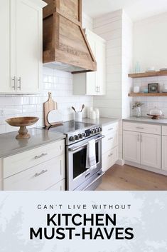 a kitchen with white cabinets and stainless steel stove top oven in front of a wooden hood