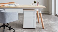 an office chair sitting next to a desk with a file cabinet on it and some books