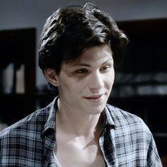 a young man with black hair wearing a plaid shirt