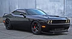 a black sports car parked in front of a metal building with its lights turned on