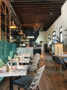 the interior of a restaurant with tables, chairs and lights hanging from the rafters