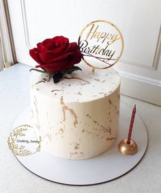 a birthday cake with a single red rose on top