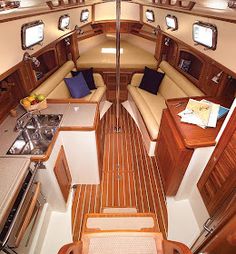 the interior of a boat with wood flooring and white walls, wooden trimming