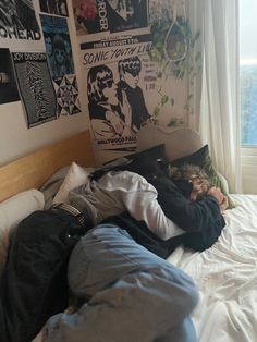 a person laying on top of a bed in a bedroom next to a large window