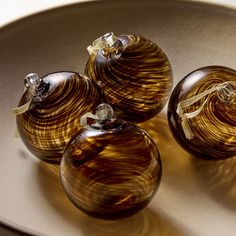 three brown glass ornaments sitting on top of a plate