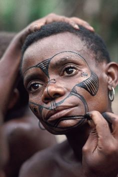 a woman with painted face and nose is holding her hand up to her face as she looks at the camera