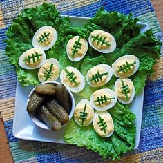 a white plate topped with lettuce covered in deviled eggs and pickles