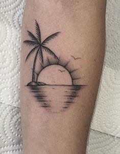 a black and white photo of a sunset with a palm tree on the beach tattoo