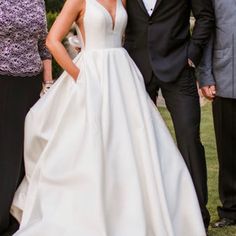 two men and a woman in formal wear standing next to each other on the grass