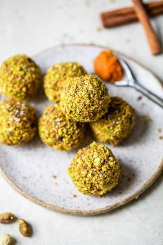 several balls of food sitting on a plate with a spoon next to it and some spices