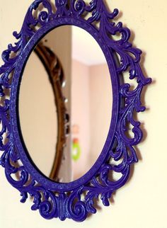 a purple mirror hanging on the wall next to a white wall with a blue frame