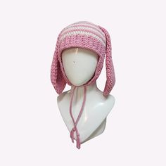 a white mannequin head wearing a pink and white knitted hat with tassels