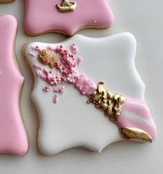 three decorated cookies with pink frosting and gold decorations