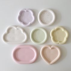 six different shapes of soap dishes on a white surface with one shaped like a heart