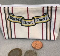 a coin purse with the words world's best dad on it next to some coins