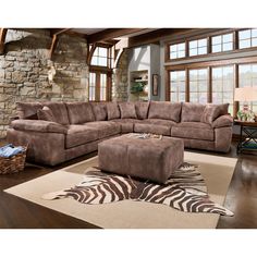 a living room with a large sectional couch and zebra rugs on the floor in front of a stone wall