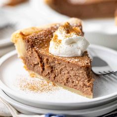 a slice of chocolate pie with whipped cream on top is sitting on a white plate