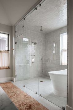 a bathroom with a large glass shower door and white bathtub in the middle of the room