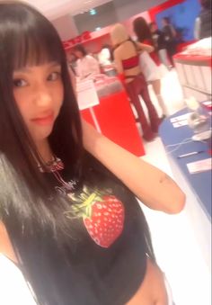 a woman with long black hair and a strawberry on her shirt is posing for the camera