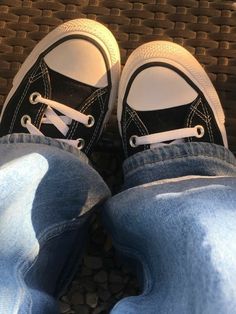 a pair of black and white shoes sitting on top of a person's feet