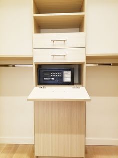 a microwave sitting on top of a wooden cabinet next to a shelf filled with drawers