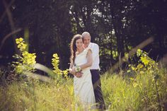 a man and woman are standing in the tall grass with yellow flowers on their wedding day