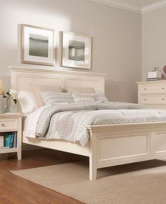 a white bed sitting on top of a wooden floor next to a dresser and mirror