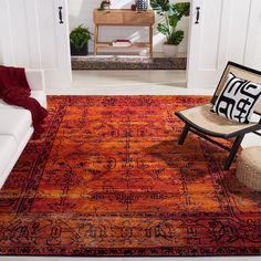 an orange and red rug in a living room with a chair on the floor next to it