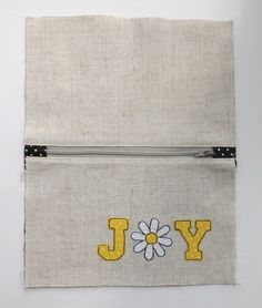 a piece of fabric with the word joy written on it and a flower in the middle