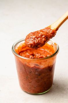 a spoon full of sauce on top of a jar