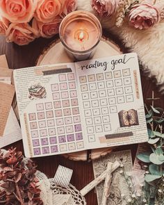 a table topped with lots of flowers next to a candle and some paper on top of it