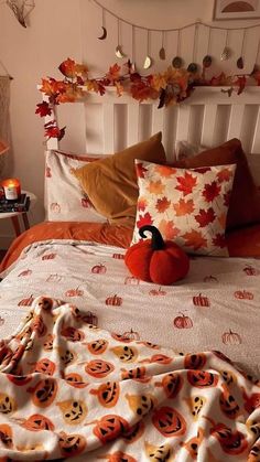 a bed topped with lots of pillows covered in pumpkins