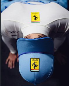 a man is upside down with his head on the back of a blue hat that has a yellow and black sticker on it