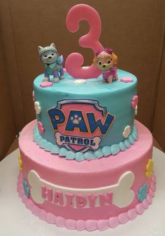 a pink and blue birthday cake with paw patrol figures