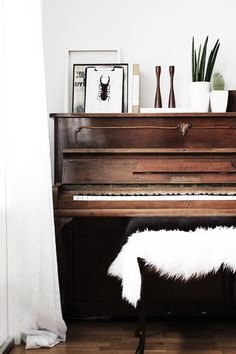 a piano with white fur on it in front of a window and potted plants