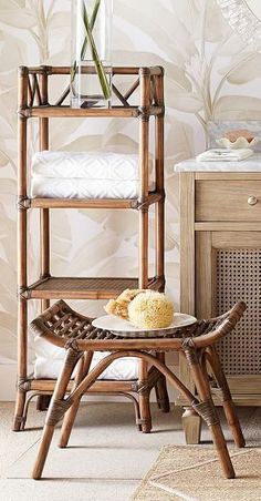 a bamboo shelf with flowers in a vase on it next to a wicker stool