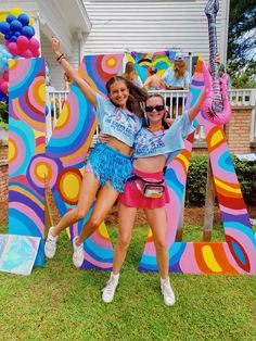 two young women are posing in front of a giant letter with balloons and guitars on it