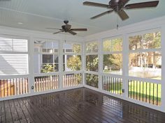 a sun room with wooden floors and ceiling fans on the windows, and white shutters