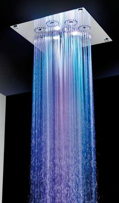 a shower head with blue and purple water flowing from it's sides in a dark room