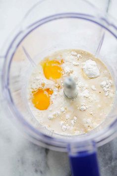 three eggs in a blender with flour on top