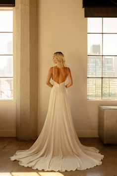 the back of a woman's wedding dress in an empty room with large windows