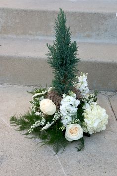 a bouquet of white flowers sitting on the ground next to some steps with plants growing out of it