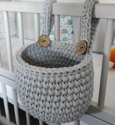 a crocheted basket hanging from the side of a baby's crib